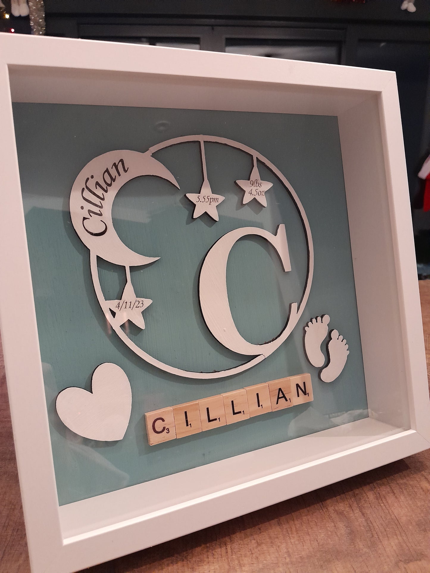 Beautiful Moon & Star wreath Frame displaying baby's name, date of birth, weight and time. Made from 3mm white mdf and set on a baby pink or blue/green background.