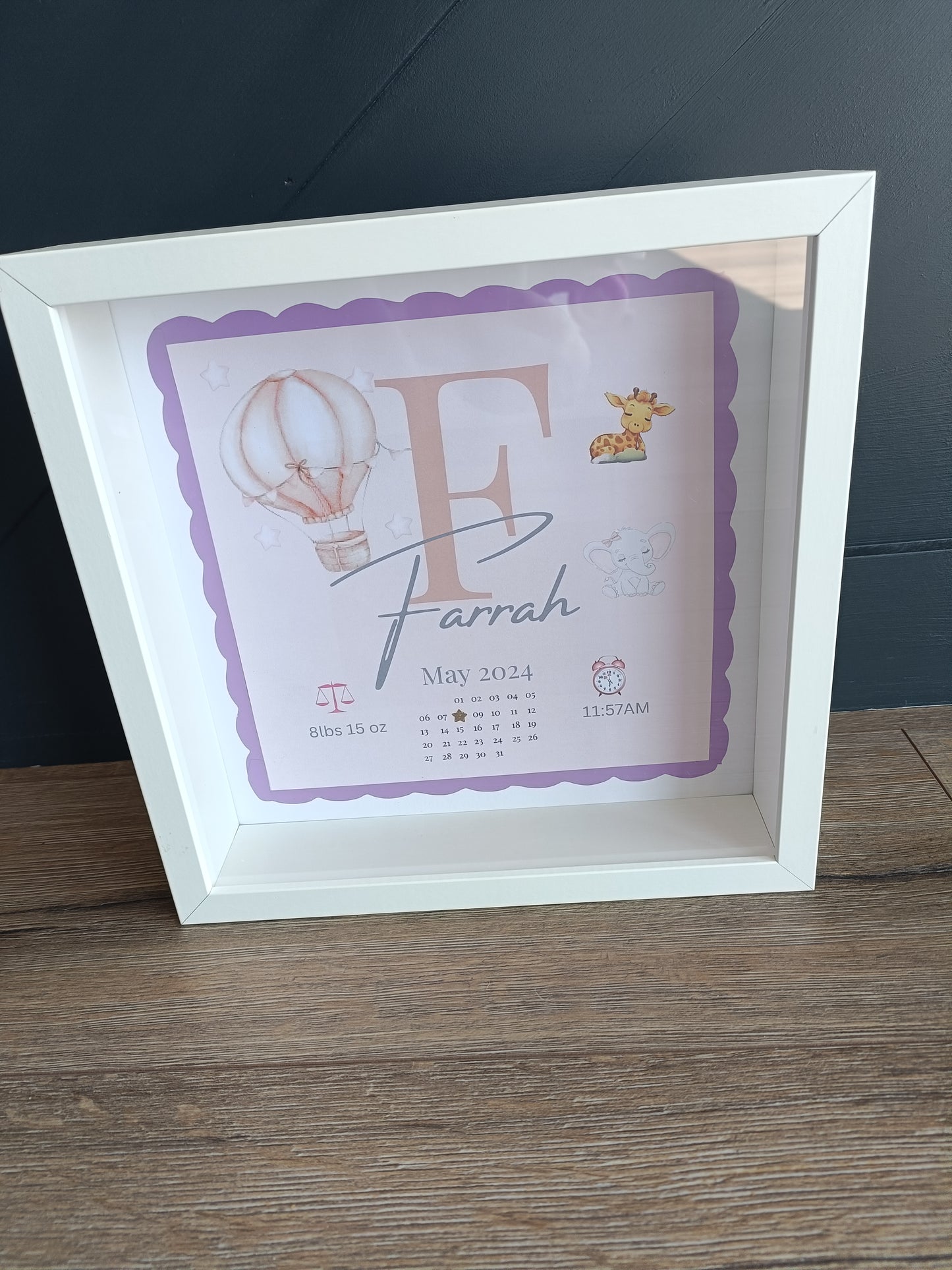 Baby initial frame with detailed print background of hot air balloon, baby giraffe and elephant. Disaplys babies name, initial, date of birth, time and weight. 