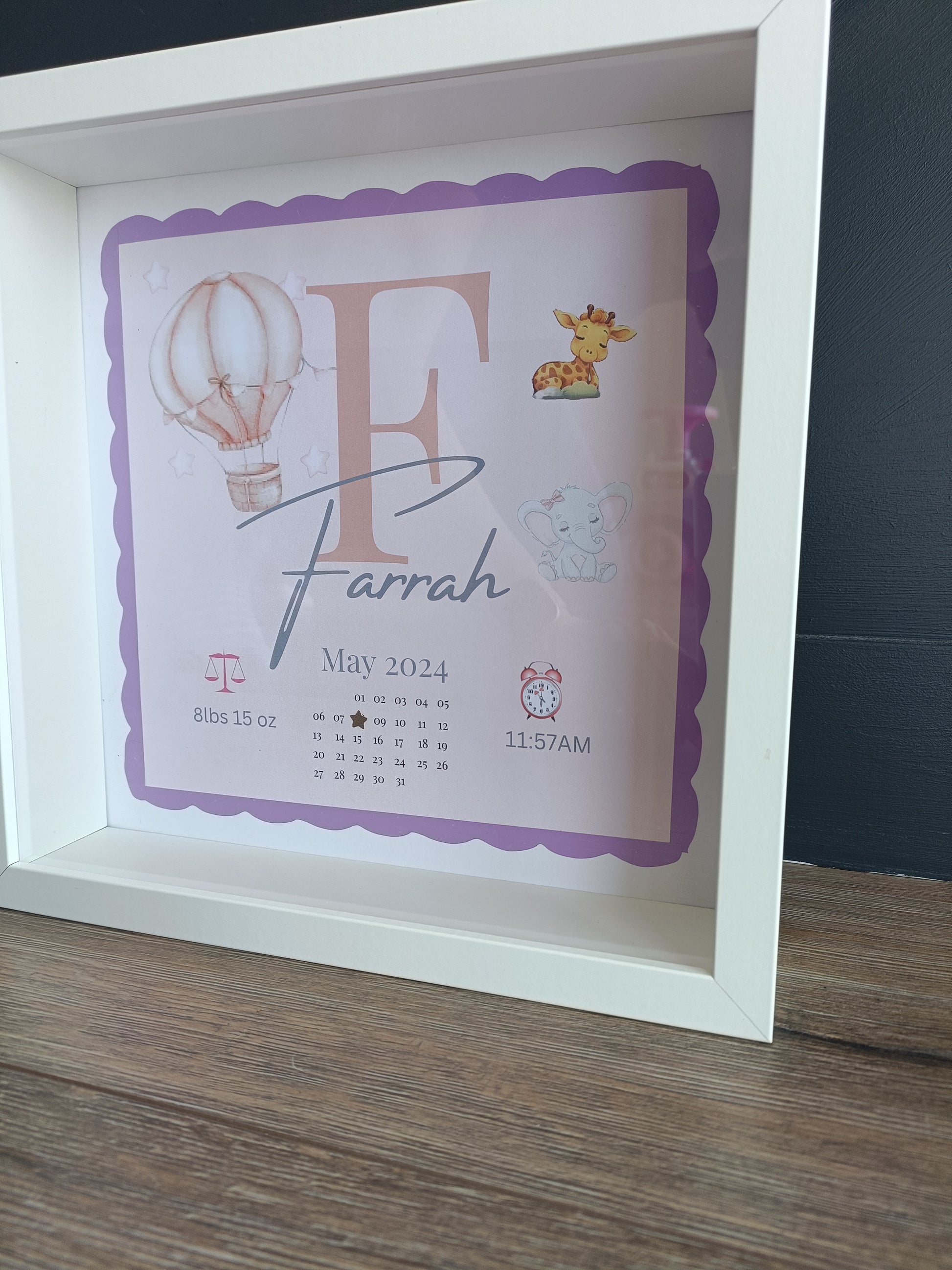 Baby initial frame with detailed print background of hot air balloon, baby giraffe and elephant. Disaplys babies name, initial, date of birth, time and weight. 